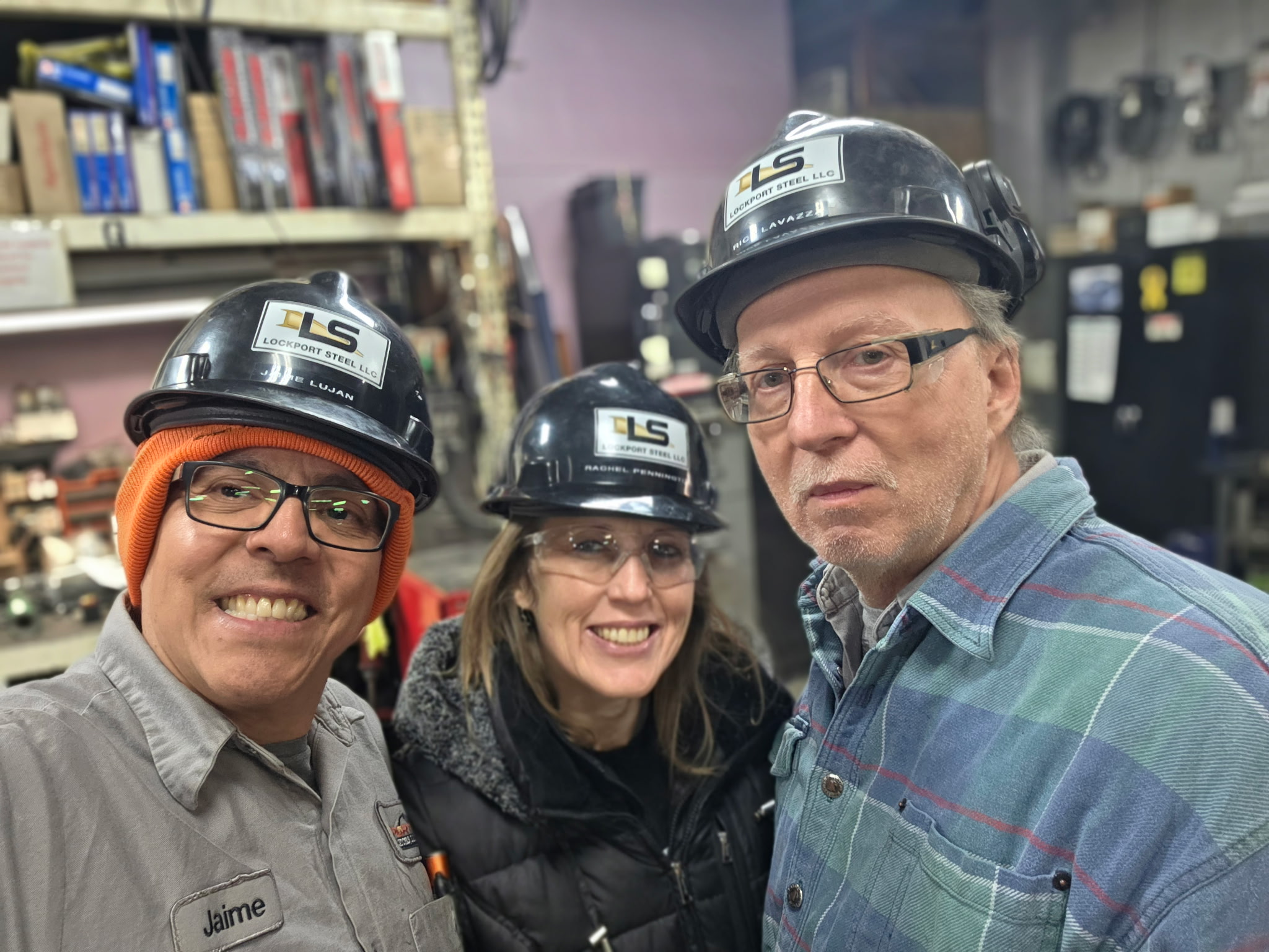 Three Lockport employees posing for a group selfie photo, all wearing Lockport Steel hard hats.